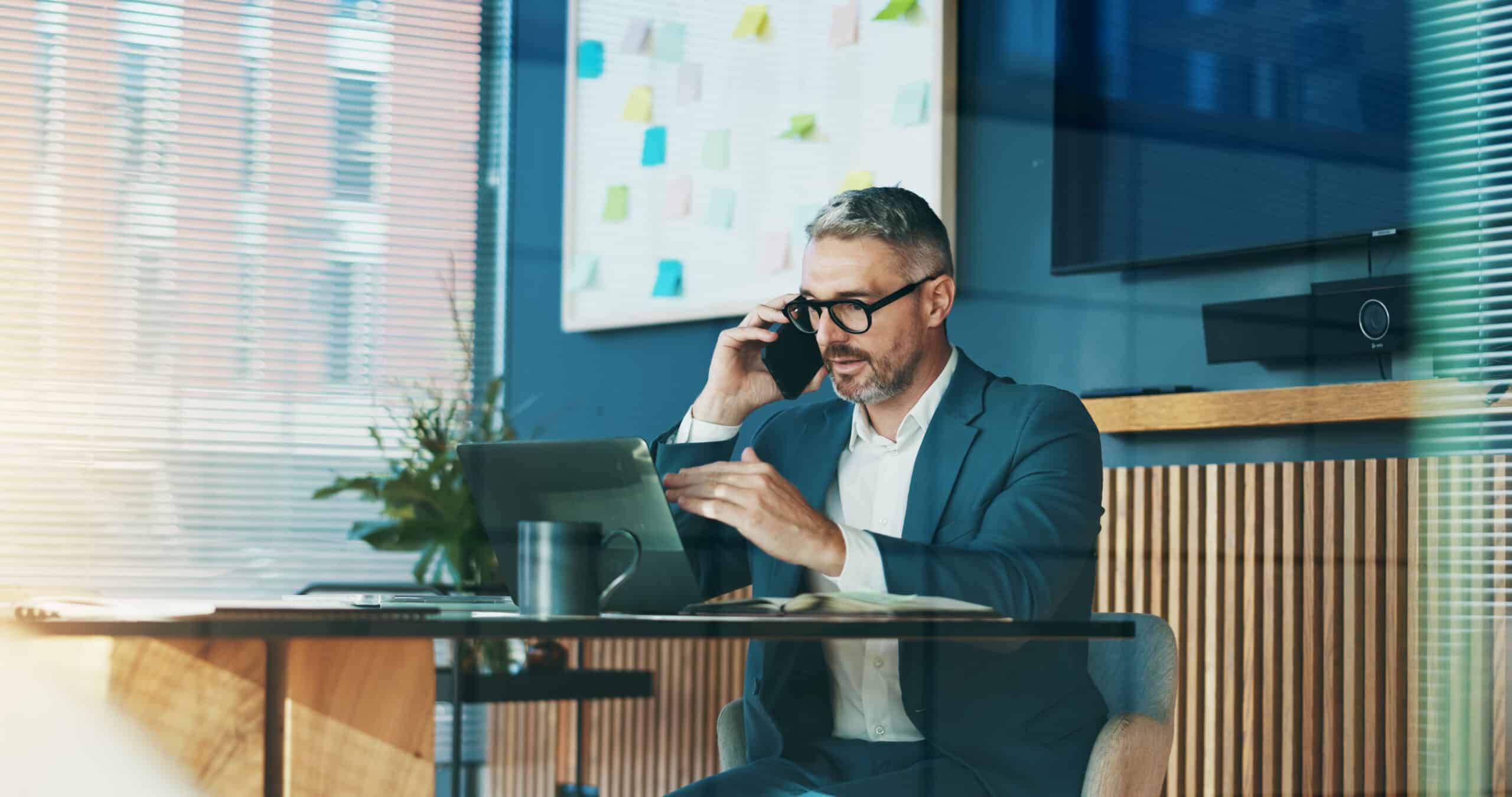 Phone call, laptop and mature man with glasses, accountant or talking to contact for tax and discussion. Business, auditor and person with mobile for communication, financial and research for funding